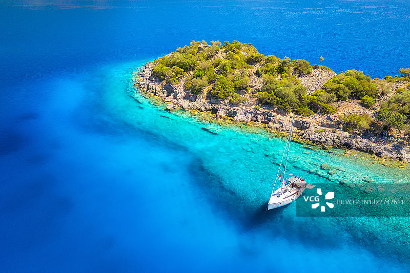 夏日日落时海上美丽的游艇鸟瞰图。土耳其的Gemiler岛。俯视图豪华游艇，石头，岩石，海滩，山和绿树。旅行。小船和清澈的蓝色海水图片素材