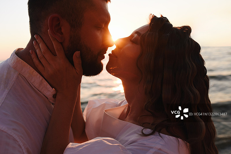 一对年轻的情侣在日落时接吻。图片素材