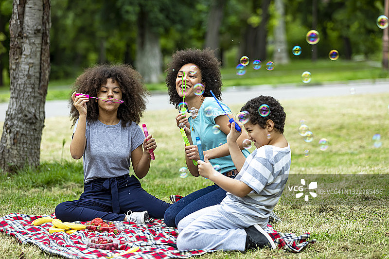 一个快乐的非裔美国人家庭正在草地上野餐。图片素材