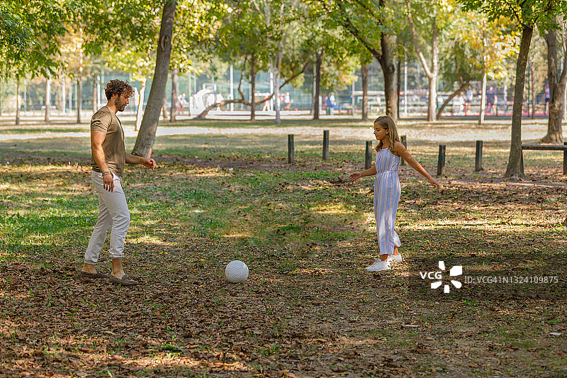 一个快乐的家庭正在草地上玩足球。图片素材