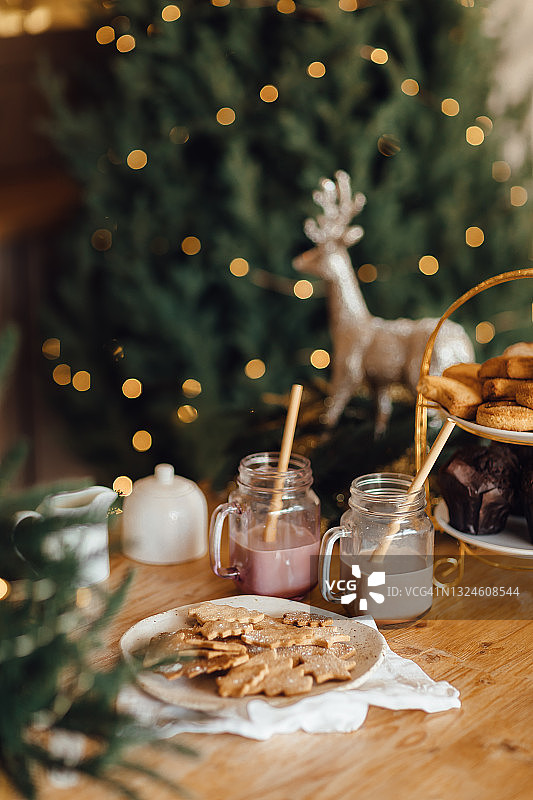 厨房桌子上的圣诞饼干和热巧克力装饰和燃烧的花环。图片素材
