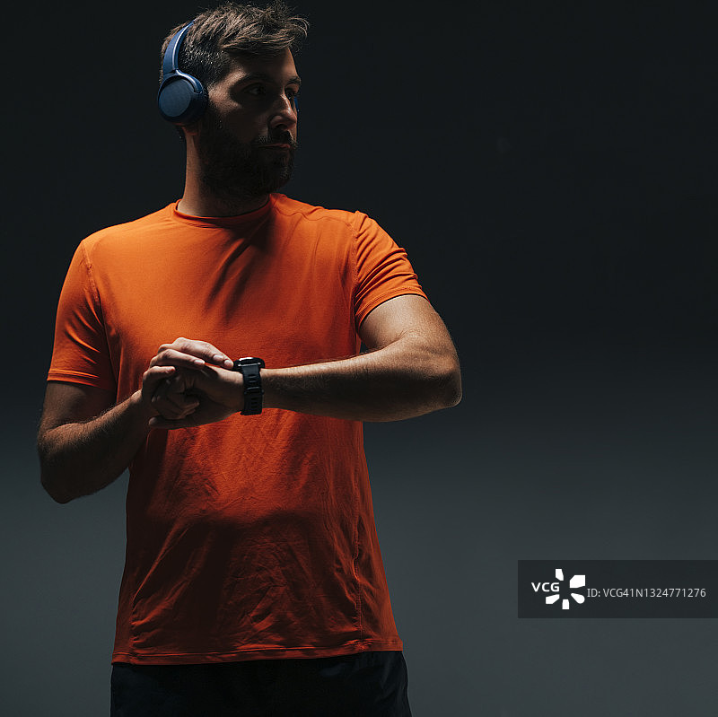 英俊的运动员听音乐和使用他的智能手表测量他的脉搏锻炼后图片素材