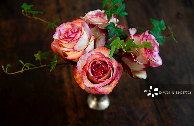 一个银色的花瓶，上面有美丽的玫瑰和常青藤。图片素材