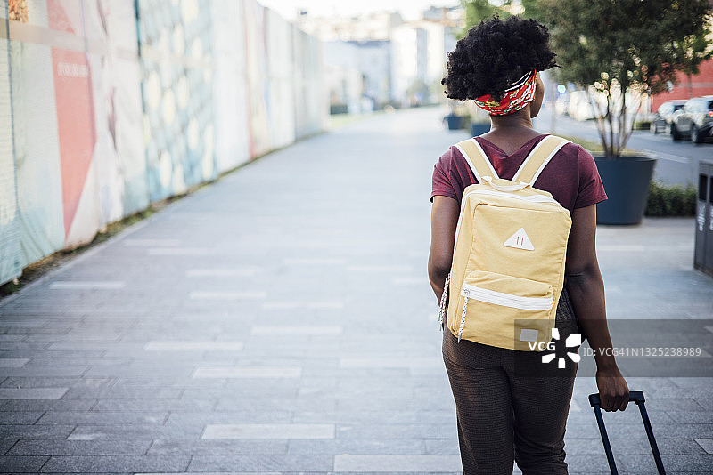 非裔美国女游客提着行李箱走在街上图片素材