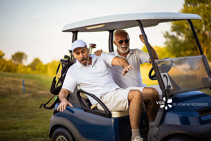 两个老朋友坐在高尔夫球车里。图片素材