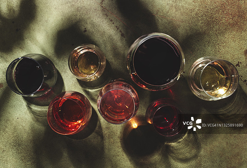 红，玫瑰和白葡萄酒在玻璃上生锈的绿色背景，俯视图。酒吧，商店，酿酒厂，品酒概念。强光和刺眼的阴影图片素材