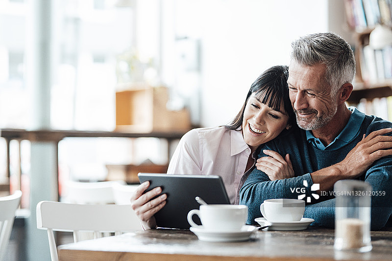 商业夫妇微笑着使用数字平板电脑在咖啡馆图片素材