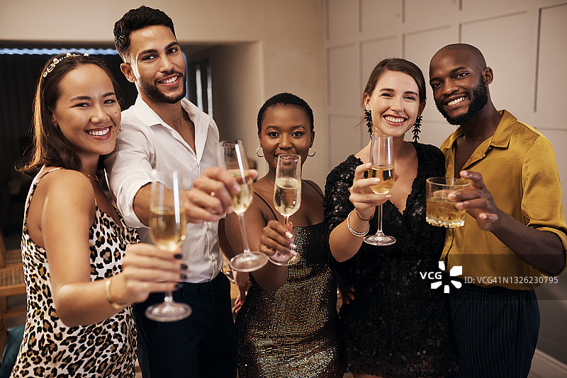 新年晚宴上，一群不同的朋友站在一起，手持香槟图片素材