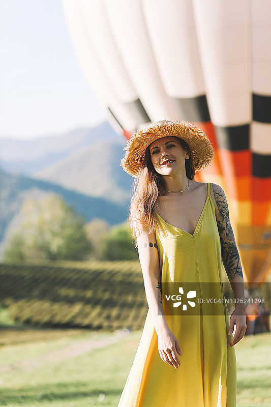 一个快乐孤独的年轻女游客，穿着明亮的黄色衣服，在绿色的茶园森林中散步和远足，背景是山里的热气球图片素材