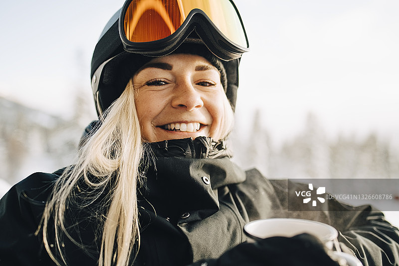 微笑的金发女人的肖像戴着滑雪镜和头盔图片素材