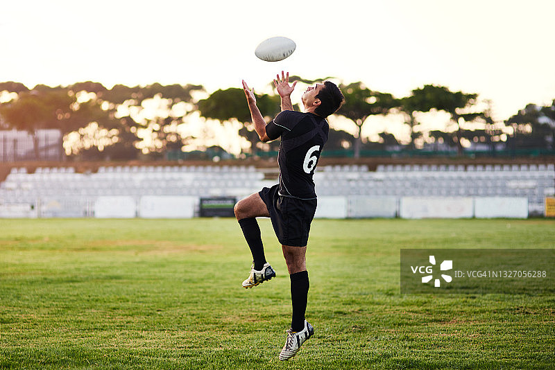 一个英俊的年轻运动员在一天的训练期间打橄榄球的全长镜头图片素材