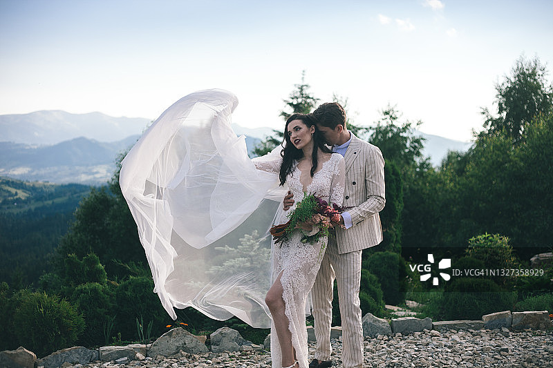 快乐的夫妇在夏天庆祝户外婚礼。山清水秀，绿林青山。图片素材