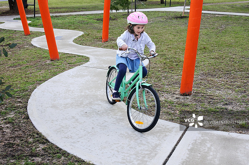 年轻的女孩在自行车道上骑自行车图片素材