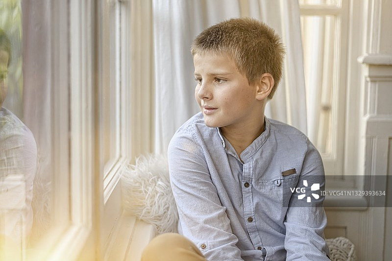 一个小男孩望向窗外的肖像图片素材