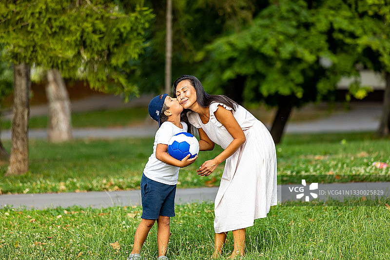 家庭的形象，母亲和儿子在公园玩球。图片素材