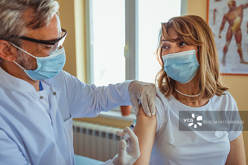 医生或护士用注射器给病人注射疫苗。适用于面膜。预防冠状病毒、COVID-19大流行和肺炎。医疗、医学。图片素材