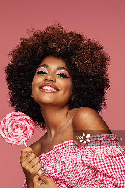 拿着棒棒糖的年轻漂亮的非洲式发型女人图片素材