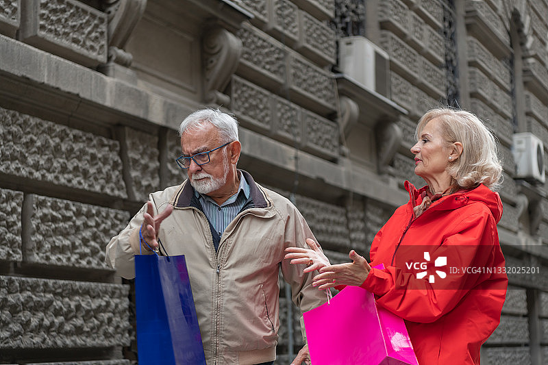 一对不高兴的退休夫妇在城市里散步，愤怒地争论着。图片素材