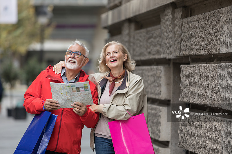 一对兴高采烈的老年游客正在用地图探索这座城市。图片素材