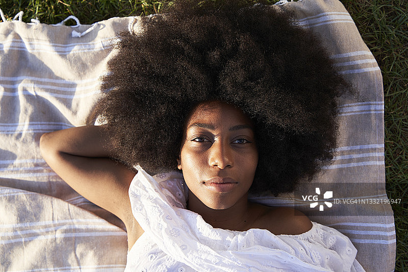 一个在公园里躺在毯子上的非洲女人图片素材