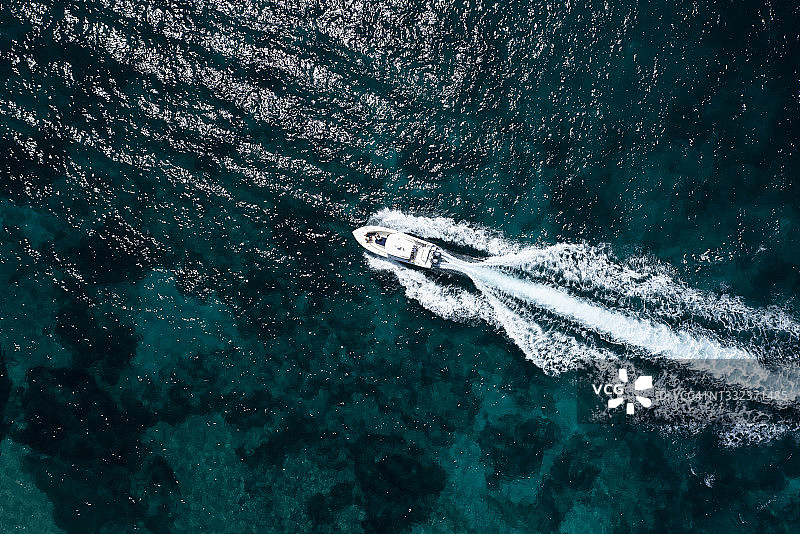从上面看，令人惊叹的鸟瞰豪华游艇航行在蓝色的水。意大利撒丁岛的翡翠海岸。图片素材