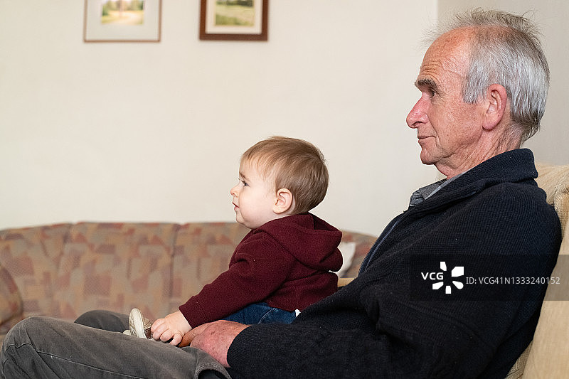 爷爷和他的孙子在看电视。图片素材