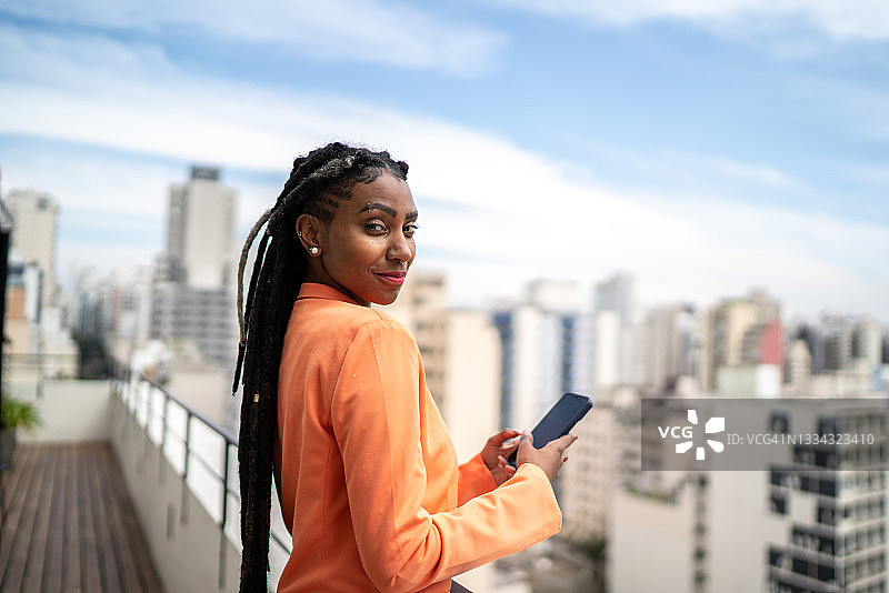 一名年轻女子在屋顶上使用智能手机图片素材