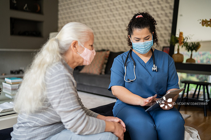 一位年长的妇女戴着防护口罩在出诊时与护士交谈图片素材