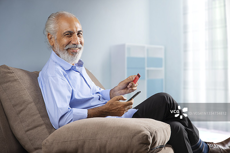一位老人快乐地坐在家里做网上交易图片素材