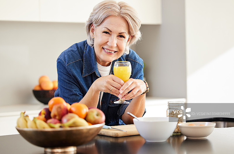 图为一位老年妇女在家里喝橙汁图片素材