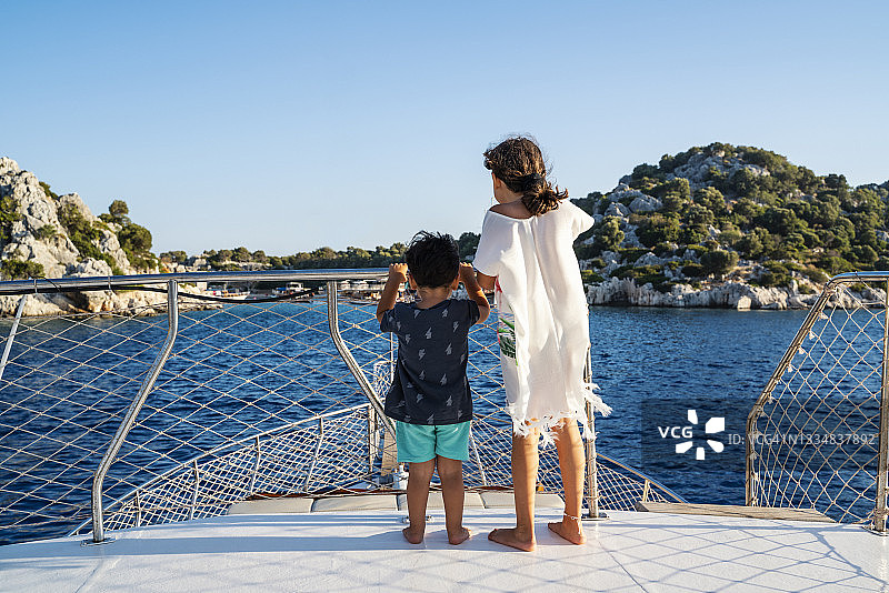 在土耳其安塔利亚凯科娃的夕阳下，可爱的小女孩和她的哥哥在帆船上旅行图片素材