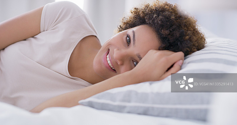 一名年轻女子躺在床上微笑图片素材