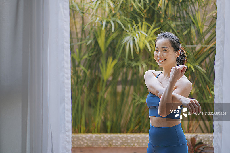 亚洲华裔美女在锻炼前的前院热身图片素材