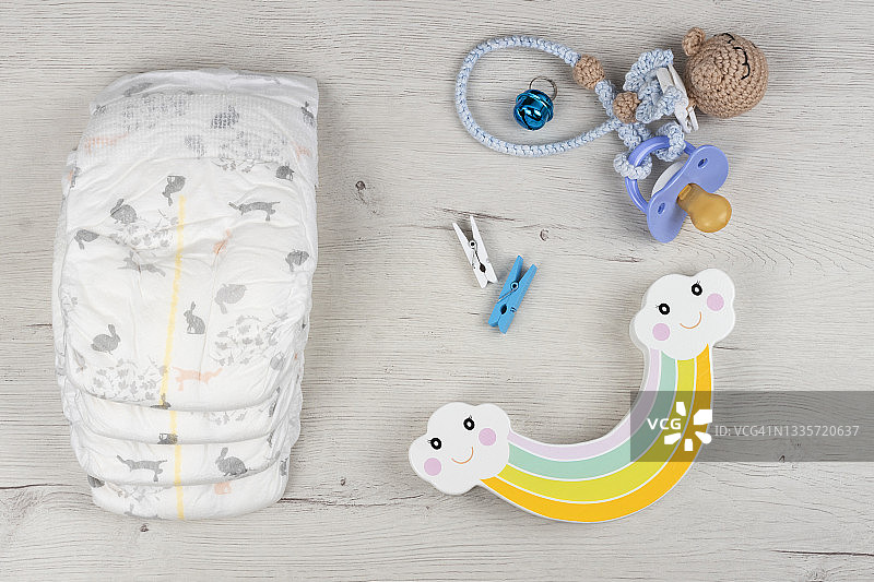 新生儿尿布，奶嘴和木制玩具在浅白色乡村背景。图片素材