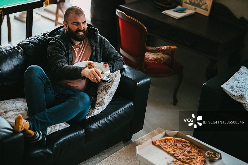 在家看电视，吃披萨外卖的男人图片素材