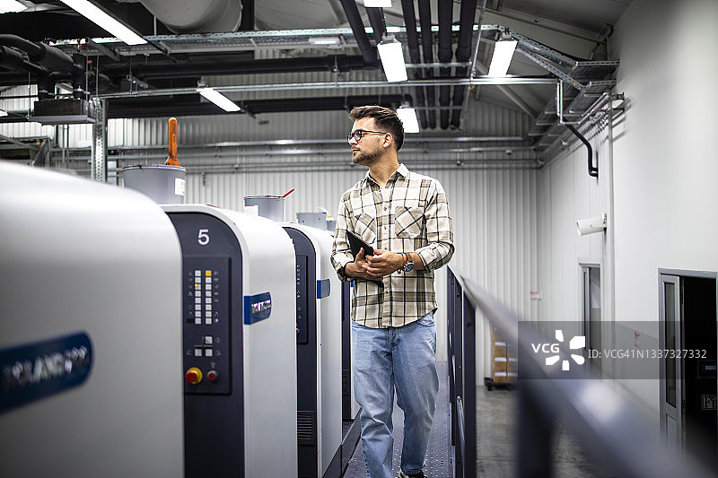 印刷工人或主管在现代胶印机上控制印刷过程和压印质量。图片素材
