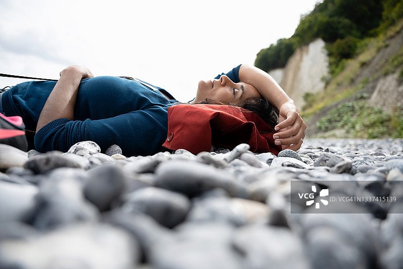 在白垩岩海岸的卵石滩休息的女人图片素材