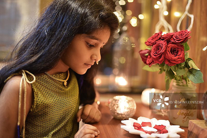 可爱的印度女孩在她的节日服装看着点燃的迪亚图片素材