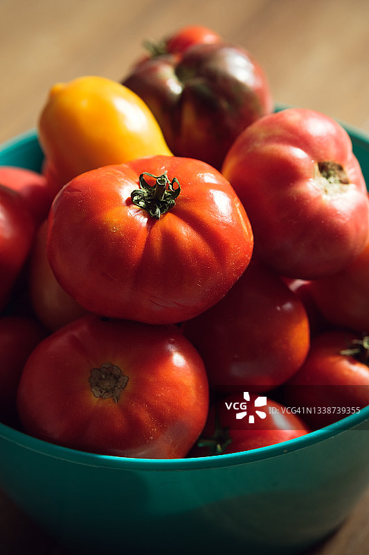 成熟的红色和黄色的西红柿在一个明亮的塑料盘子或杯子，在木制餐桌上。素食，纯素食和生的食物食物和饮食。有机自制农产品。在菜园，菜园，别墅里收获。食品的背景。图片素材
