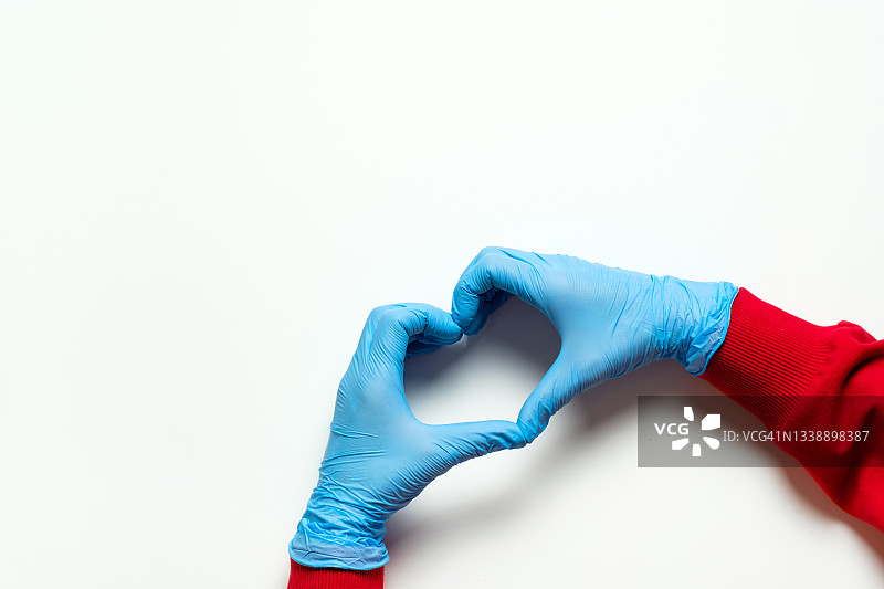 心形符号由戴着蓝色医用防护手套的心脏病专家、医务工作者、医生或实验室助理的手制作而成。照顾心脏的健康保健医学的概念，预防心脏病。图片素材