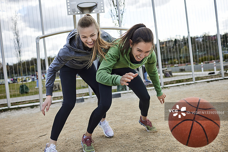 两个快乐的年轻女子在室外球场打篮球图片素材