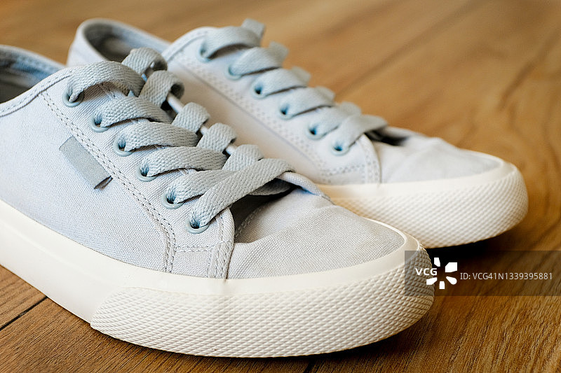 新的干净的现代运动鞋为一个女人，少年或女孩。鞋子放在家里或室内的木地板上。时尚时尚的生活方式。文本空间的副本。图片素材
