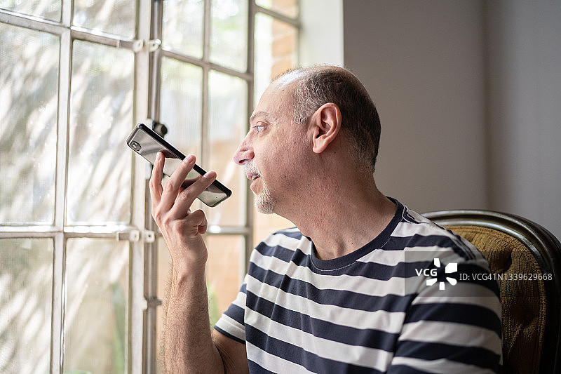 一个在家里用智能手机聊天的成熟男人图片素材