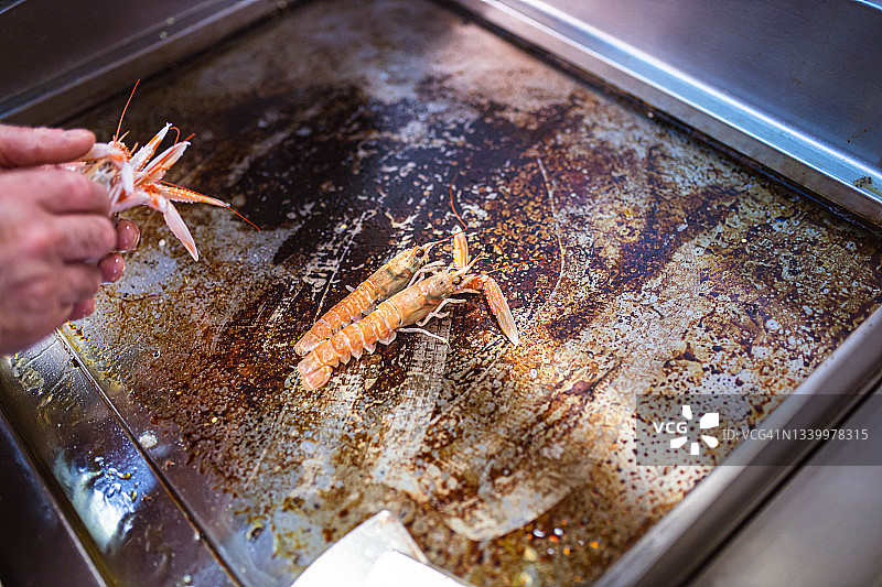 厨师把虾放在餐厅厨房的烤架上图片素材