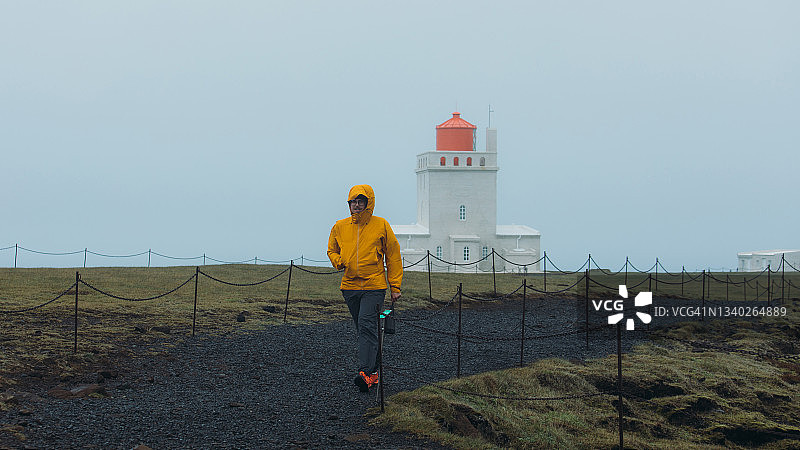 在冰岛，一名游客走在灯塔附近，感到敬畏图片素材