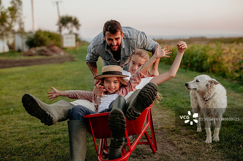 幸福的家庭在农场的独轮手推车上图片素材