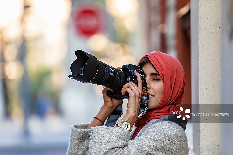 快乐的女人在度假，用相机在城市的街道上拍照。图片素材
