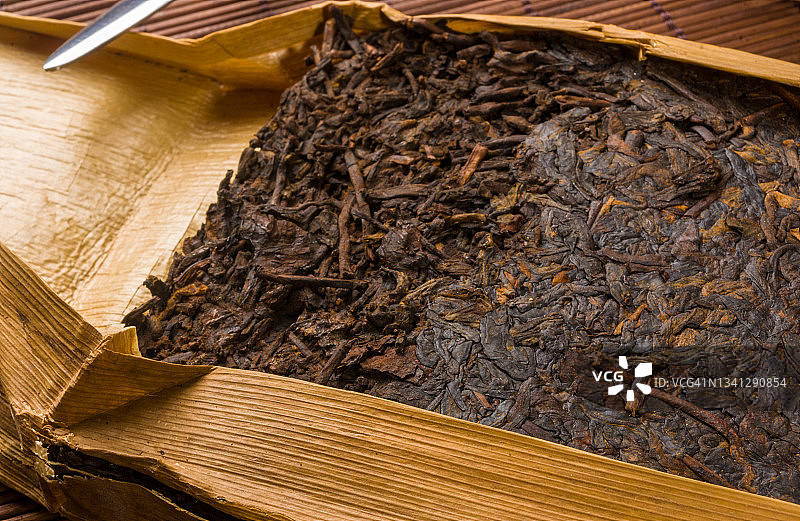 中国压普洱茶在竹叶包装和茶刀在竹席，特写，宏观图片素材