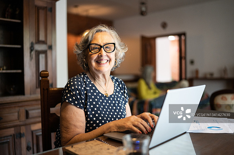 一位高级女性在家里使用笔记本电脑的肖像图片素材