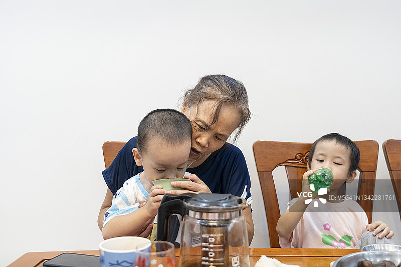 奶奶和她的孙子孙女们在一起吃早餐，喝茶图片素材